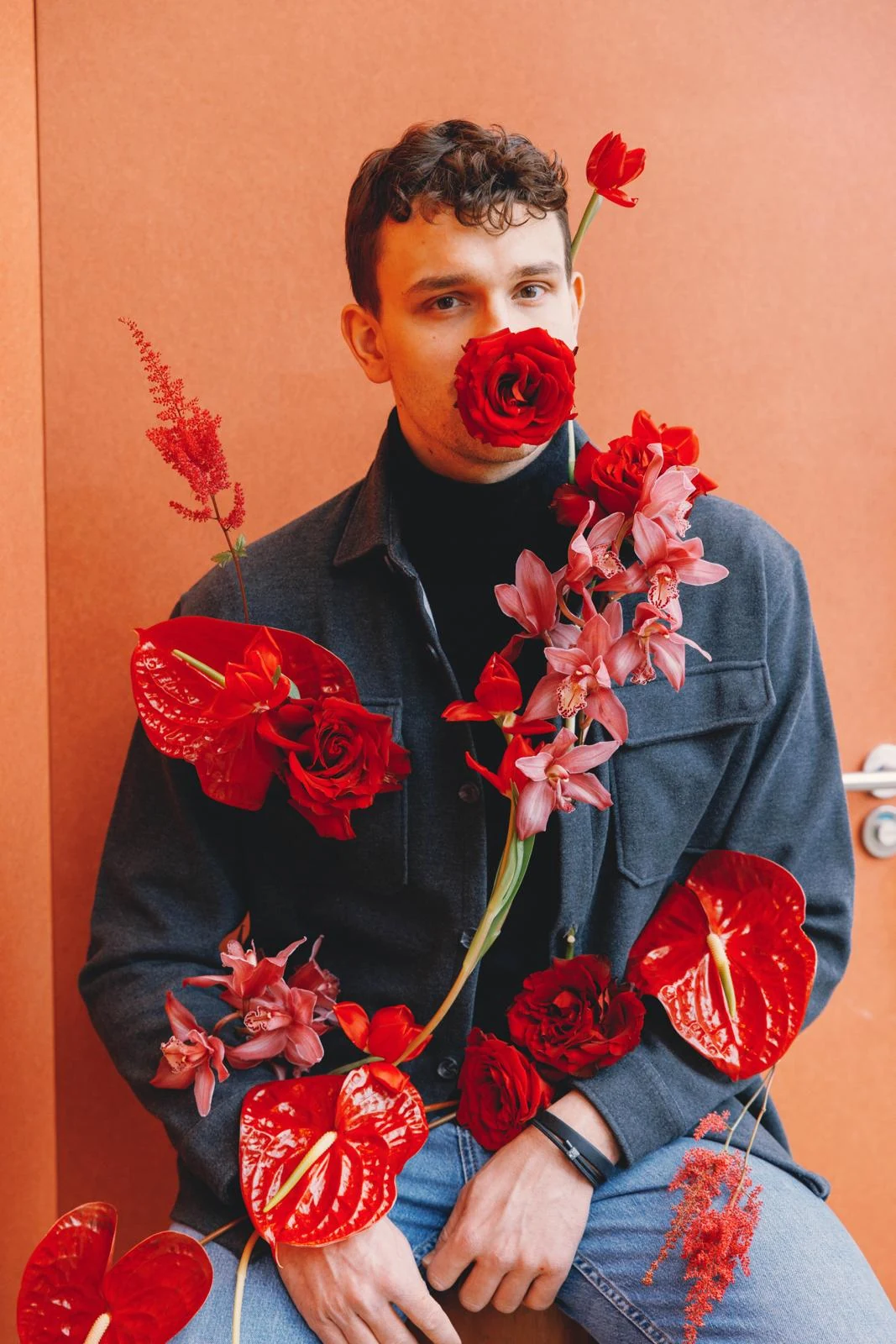 Portrait of a man surrounded by vivid red flowers