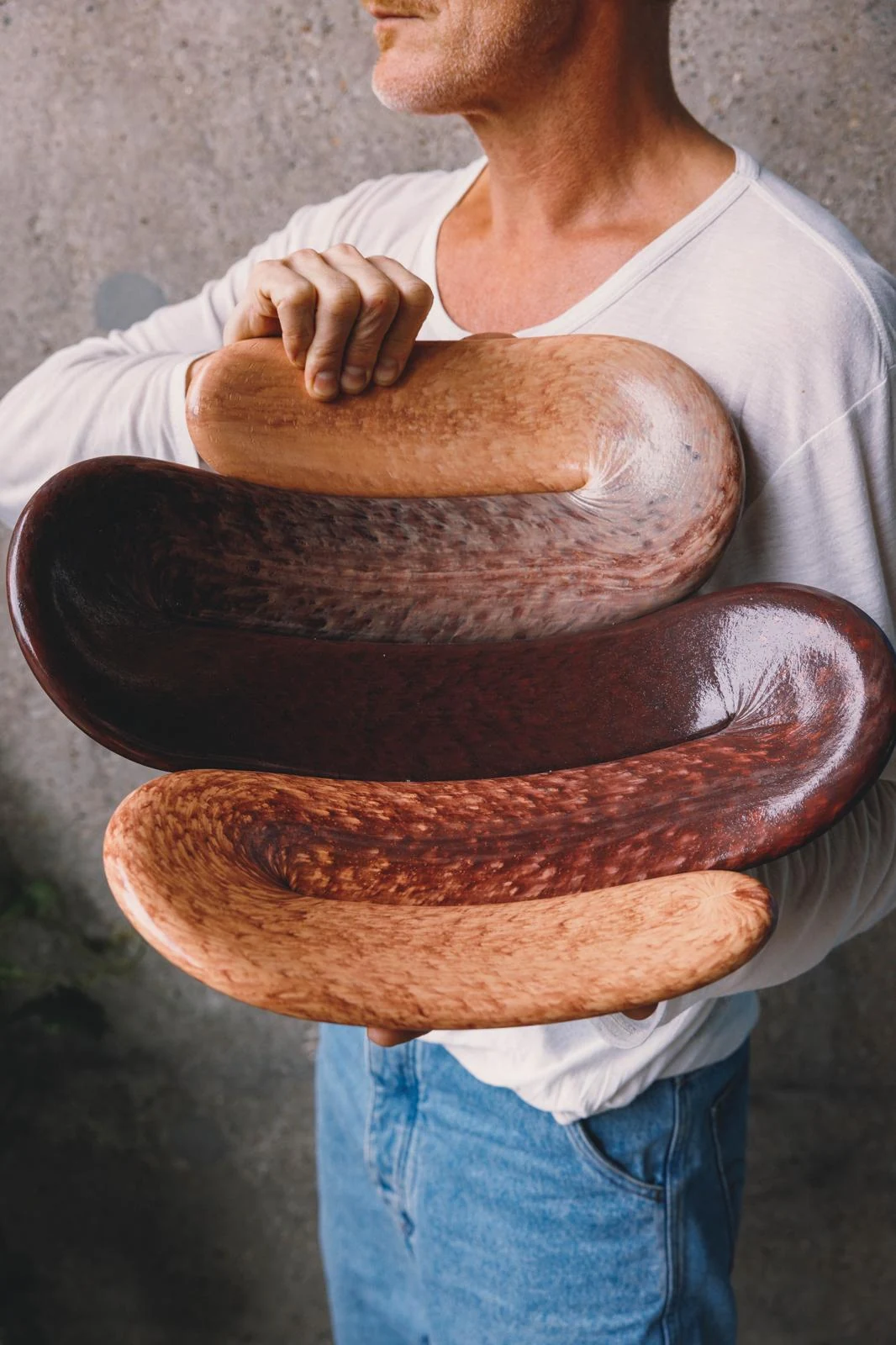 Man holding a stack of polished wooden sculptural forms